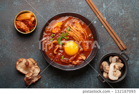 Traditional Korean kimchi jjigae hot soup or stew with egg yolk in black rustic bowl on dark background top view Traditional Korean kimchi jjigae hot soup or stew with egg yolk in black rustic bowl on dark background top view 132187093