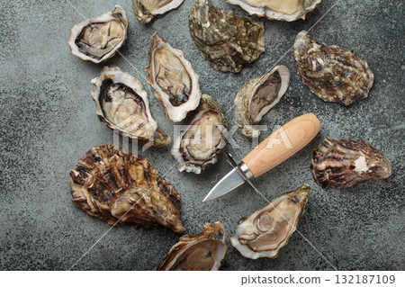 Fresh open and closed oysters with oyster knife on gray background top view Fresh open and closed oysters with oyster knife on gray background top view 132187109