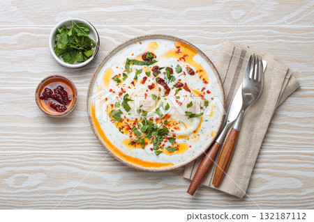 Turkish eggs cilbir, Middle Eastern style breakfast on white wooden background table top view Turkish eggs cilbir, Middle Eastern style breakfast on white wooden background table top view 132187112
