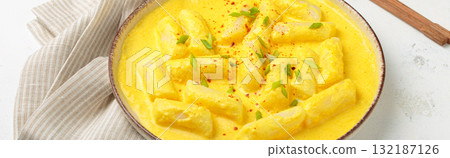 Traditional korean tteokbokki in creamy cheese sauce with garnish, wooden chopsticks on rustic white background angle view Traditional korean tteokbokki in creamy cheese sauce with garnish, wooden chopsticks on rustic white background angle view 132187126