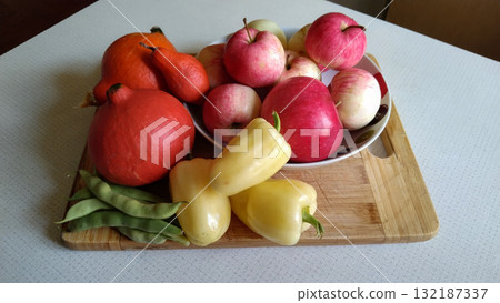 A wooden board with a variety of fruits and vegetables on it. 132187337