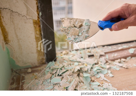 Scraping off old paint layers from wall surfaces during the renovation process is essential 132187508