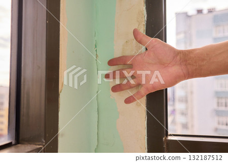 Conducting a Thorough Hand Inspection of Wall Damage in a Modern Apartment Space 132187512