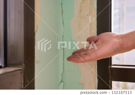 Conducting a Thorough Hand Inspection of Wall Damage in a Modern Apartment Space 132187513