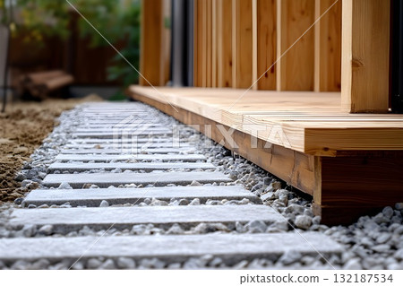 Stone step walkway with gravel infill beside wooden deck in landscaped backyard 132187534