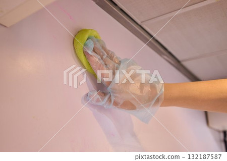 Cleaning a wall with a sponge and durable glove requires attention to detail and hygiene Cleaning a wall with a sponge and durable glove requires attention to detail and hygiene 132187587