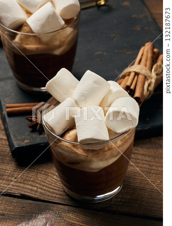 Glasses of hot chocolate with fluffy marshmallows on a wooden table. 132187673