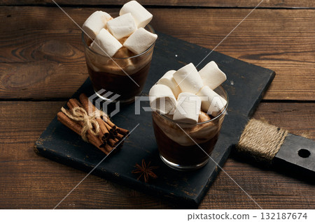Glasses of hot chocolate with fluffy marshmallows on a wooden table. 132187674
