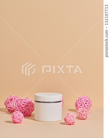 An unmarked white cosmetic jar among decorative pink rattan balls 132187713