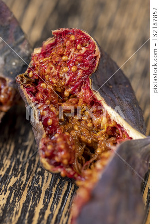 moldy whole overripe and spoiled figs with flesh and seeds on a table, moldy spoiled figs with lots of grains and red spoiled flesh on a wooden table 132187852