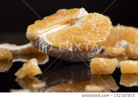 an orange citrus on a black mirror surface, ripe sweet and juicy citrus is reflected on the black surface an orange citrus on a black mirror surface, ripe sweet and juicy citrus is reflected on the black surface 132187853