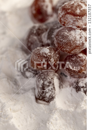 dried kumquat and powdered white sugar, sweet dried orange kumquat fruits in white powdered sugar, closeup dried kumquat and powdered white sugar, sweet dried orange kumquat fruits in white powdered sugar, closeup 132187857