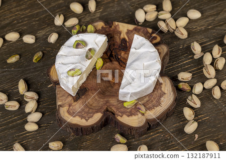 green pistachios and cheese in a white mold, delicious white soft cheese in a mold cut in the center and salted pistachios with and without cracked shells 132187911