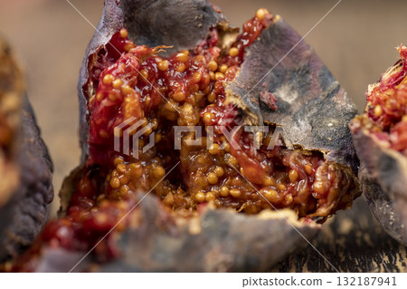 moldy whole overripe and spoiled figs with red flesh and seeds , moldy spoiled figs with lots of grains and red spoiled flesh on a wooden table 132187941