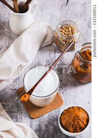 Miso-Spiked latte in a glass and a bowl of miso paste on the table vertical view 132188011
