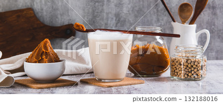 Miso-Spiked latte in a glass and a bowl of miso paste on the table web banner 132188016
