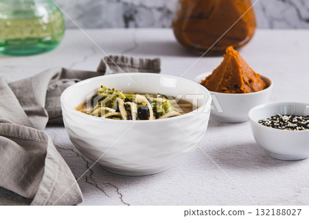 Delicious miso soup with noodles and broccoli in a bowl on the table Delicious miso soup with noodles and broccoli in a bowl on the table 132188027