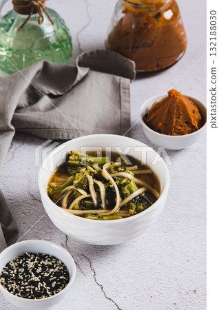 Asian broccoli noodle miso soup in a bowl on the table vertical view Asian broccoli noodle miso soup in a bowl on the table vertical view 132188030