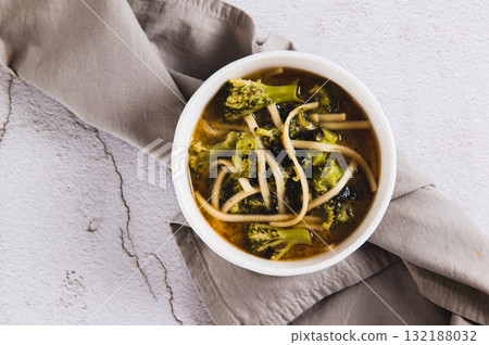 Close up of delicious miso soup with noodles and broccoli in a bowl on the table top view Close up of delicious miso soup with noodles and broccoli in a bowl on the table top view 132188032