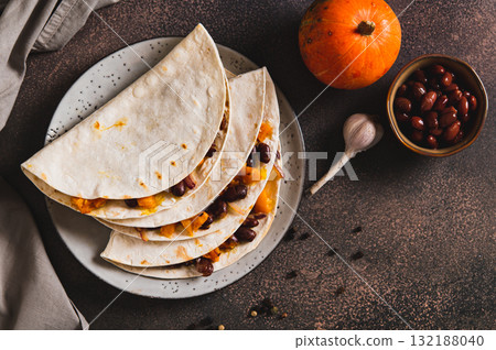 Delicious tacos with baked pumpkin, beans and cheese on a plate on the table top view 132188040