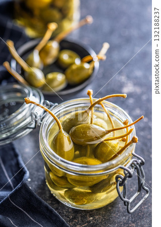 Pickled capers berries in jar on black table. Pickled capers berries in jar on black table. 132188237