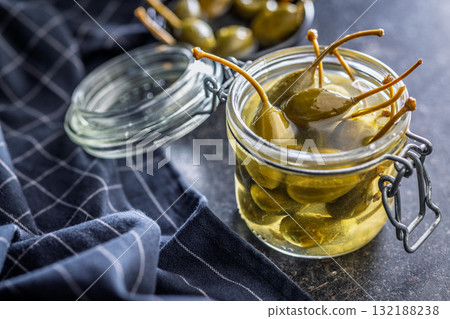 Pickled capers berries in jar on black table. 132188238