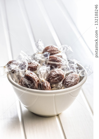 Sweet bonbon candies wrapped in foil on white table. 132188246