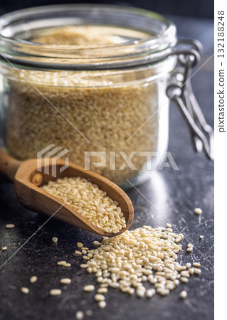 Roasted sesame seeds on scoop on black table. Roasted sesame seeds on scoop on black table. 132188248