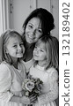 A woman and two young girls pose for a picture together 132189402