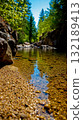 A small stream in the middle of a forest filled with rocks and pebbles 132189413