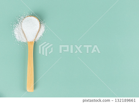 Natural stevia sweetener in a spoon on a blue background. Top view. Copy space. Natural stevia sweetener in a spoon on a blue background. Top view. Copy space. 132189661