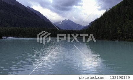 Turquoise lake reflecting mountains and cloudy sky. Media 132190329