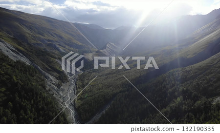 Sun shining through clouds illuminating mountain valley. Media 132190335