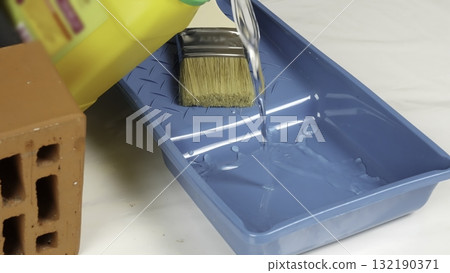 Pouring primer liquid into a blue tray for construction work. Creative 132190371