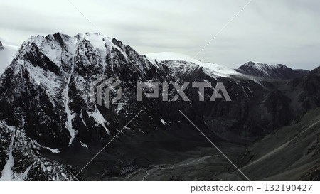 Majestic snow capped mountain range under cloudy sky. Media Majestic snow capped mountain range under cloudy sky. Media 132190427