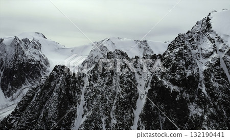 Majestic snow capped mountain peaks under a cloudy sky. Media Majestic snow capped mountain peaks under a cloudy sky. Media 132190441
