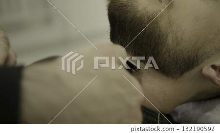 Professional barber trimming man's beard with electric razor. Clip Professional barber trimming man's beard with electric razor. Clip 132190592