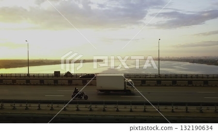 Motorcyclist riding over river bridge at sunset. Clip Motorcyclist riding over river bridge at sunset. Clip 132190634