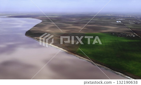 Aerial view flying over pink salt lake and green fields. Media Aerial view flying over pink salt lake and green fields. Media 132190638