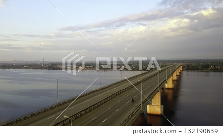 Aerial view of a motorcyclist riding on a long bridge at sunrise. Clip 132190639