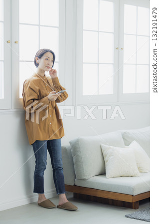 一個女人在客廳裡看著她的智能手機 132191479