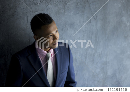 A man in a suit standing against a wall A man in a suit standing against a wall 132191536
