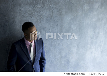 A man in a suit standing against a wall A man in a suit standing against a wall 132191537