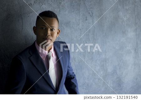 一個穿著西裝的男人靠著牆站著 132191540