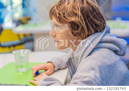Teenage boy wearing safety glasses prepares to conduct chemistry experiments, representing STEM education, curiosity, and the excitement of hands-on scientific discovery Teenage boy wearing safety glasses prepares to conduct chemistry experiments, representing STEM education, curiosity, and the excitement of hands-on scientific discovery 132191743