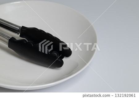 White plate and black tongs Simple cooking utensils 132192061