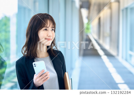 Young businesswoman with smartphone in the hallway Young businesswoman with smartphone in the hallway 132192284