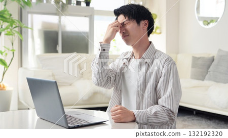 Asian man's eyes hurt from working on a computer 132192320