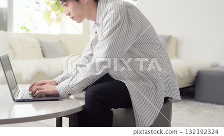 Asian man working on a computer with bad posture 132192324