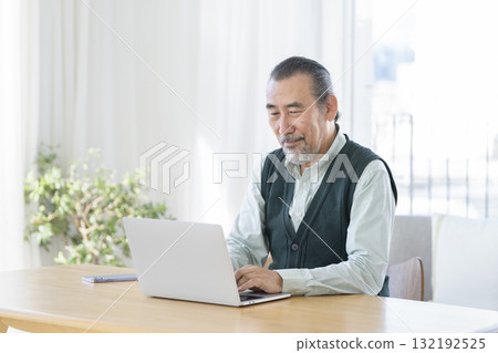 A man in his 70s working on a laptop 132192525